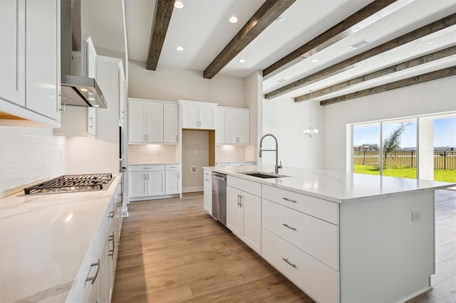 kitchen with a sink, light wood finished floors, stainless steel appliances, white cabinetry, and tasteful backsplash