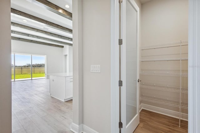 corridor featuring baseboards and light wood-style flooring