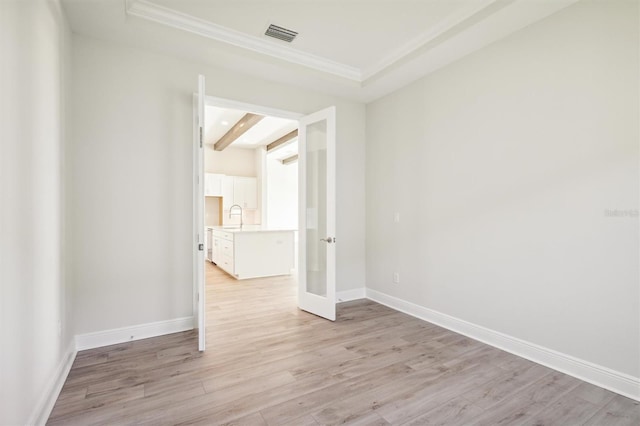 unfurnished room featuring beamed ceiling, crown molding, sink, and light wood-type flooring