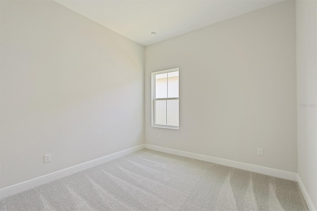 empty room featuring baseboards and light carpet