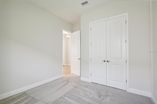 unfurnished bedroom with light carpet and a closet