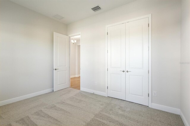 unfurnished bedroom featuring baseboards, carpet, a closet, and visible vents