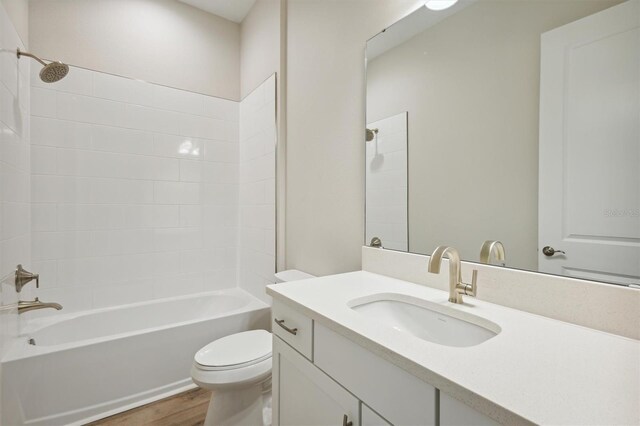 bathroom with vanity, toilet, wood finished floors, and shower / washtub combination