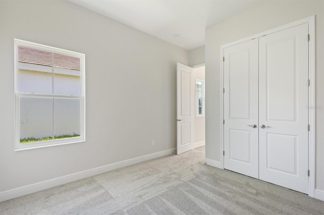 unfurnished bedroom with light carpet and a closet