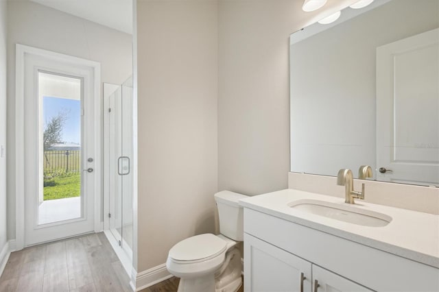 full bathroom featuring a shower stall, wood finished floors, vanity, baseboards, and toilet