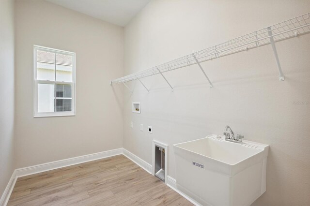 clothes washing area featuring laundry area, baseboards, hookup for a washing machine, light wood-type flooring, and electric dryer hookup