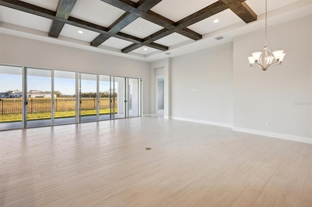 spare room featuring beam ceiling, coffered ceiling, a notable chandelier, a towering ceiling, and light wood-type flooring