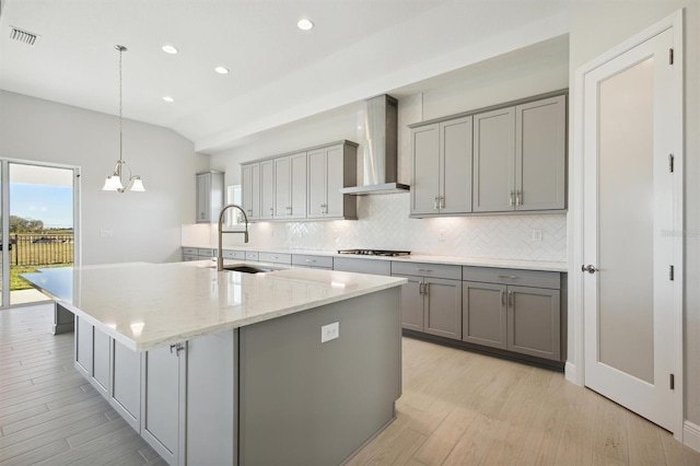 kitchen featuring gray cabinetry, pendant lighting, sink, wall chimney exhaust hood, and stainless steel gas cooktop