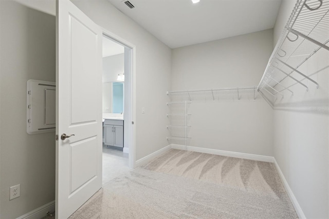 walk in closet featuring light colored carpet