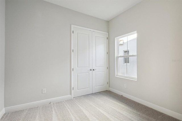 unfurnished bedroom featuring light carpet and a closet