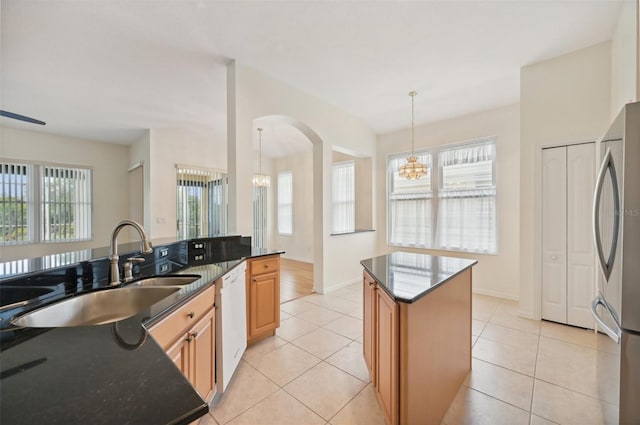 kitchen featuring pendant lighting, a center island, white dishwasher, light tile patterned floors, and stainless steel refrigerator