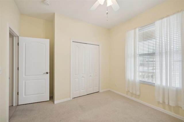 unfurnished bedroom with ceiling fan, multiple windows, light carpet, and a closet