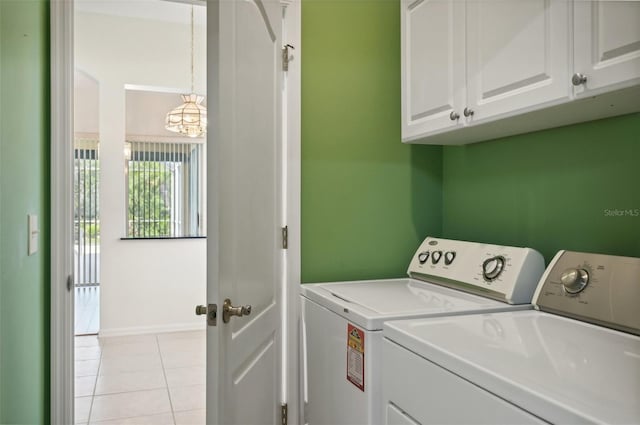 clothes washing area featuring washer and clothes dryer, light tile patterned flooring, and cabinets