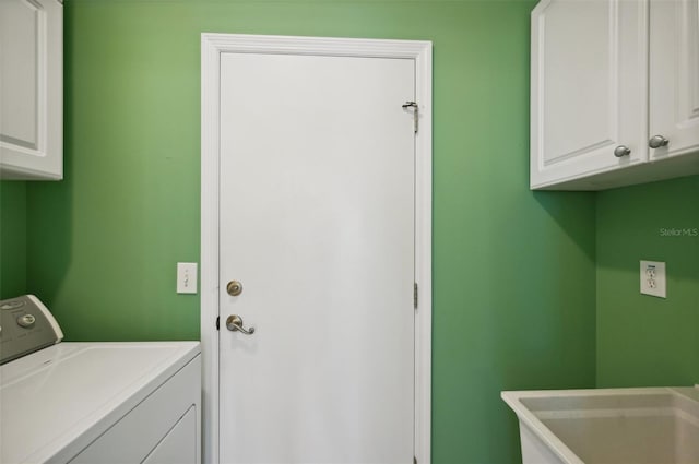 clothes washing area with cabinets, washer / dryer, and sink