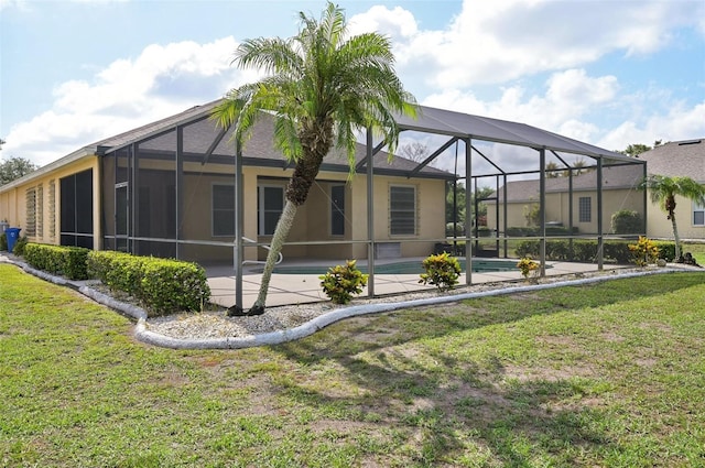 back of house featuring a lawn, glass enclosure, and a patio