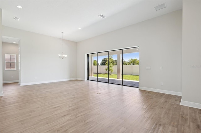 spare room featuring a chandelier and light hardwood / wood-style floors