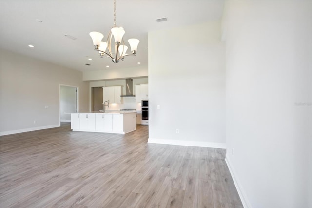 unfurnished living room featuring an inviting chandelier, light hardwood / wood-style floors, and sink