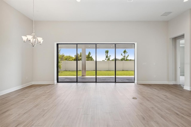 spare room with light hardwood / wood-style floors and a notable chandelier