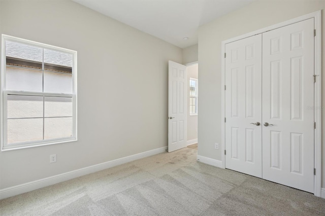 unfurnished bedroom featuring a closet and light carpet