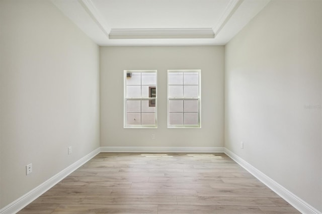 empty room featuring crown molding, a raised ceiling, and light hardwood / wood-style floors