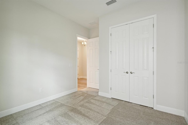 unfurnished bedroom with a closet and light colored carpet