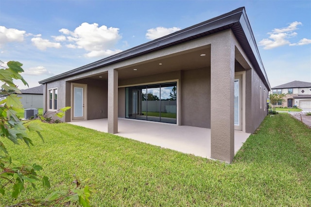 back of house featuring a yard, central AC unit, a garage, and a patio