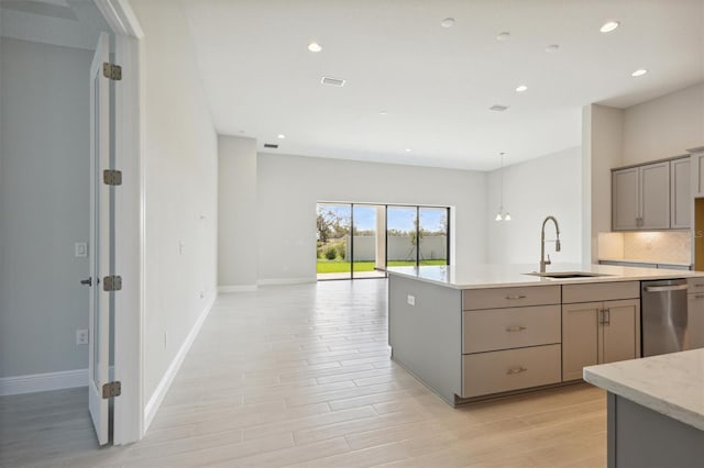 kitchen with stainless steel dishwasher, sink, gray cabinetry, and light wood-type flooring