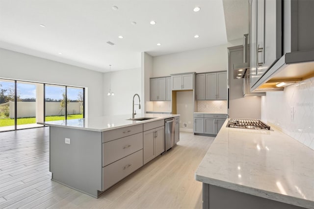 kitchen featuring a large island, sink, light stone countertops, appliances with stainless steel finishes, and tasteful backsplash