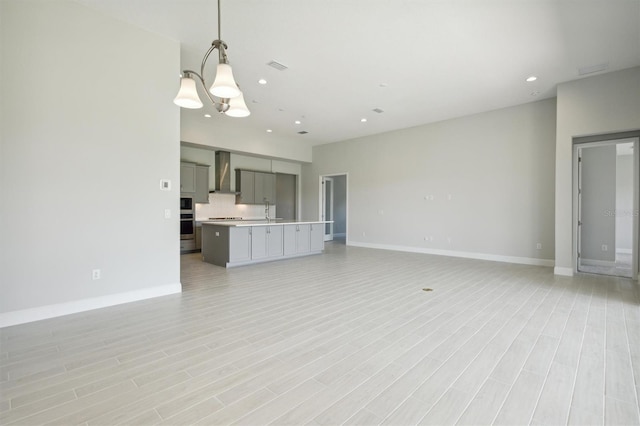 unfurnished living room featuring sink, light hardwood / wood-style flooring, and a chandelier