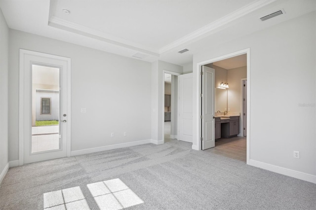 unfurnished bedroom featuring connected bathroom, a tray ceiling, and light colored carpet