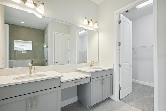 bathroom featuring vanity, a tile shower, and tile patterned flooring