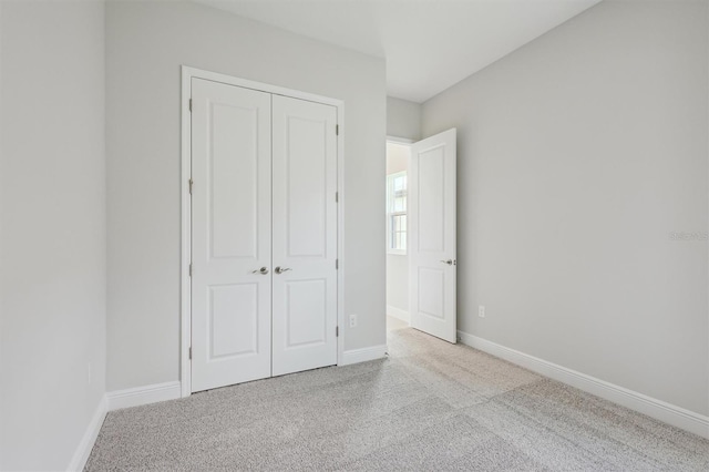 unfurnished bedroom featuring light carpet and a closet