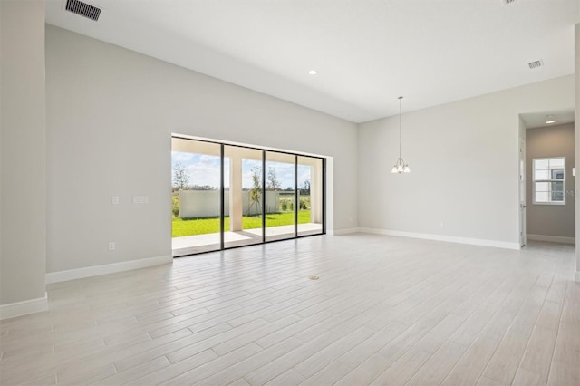 spare room with light hardwood / wood-style floors and a notable chandelier