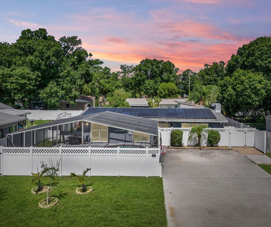 view of front of house with a lawn, solar panels, and glass enclosure