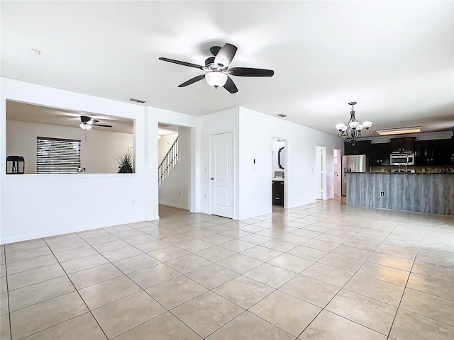 unfurnished living room featuring ceiling fan with notable chandelier and light tile patterned floors