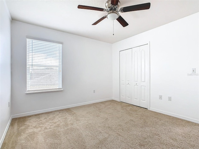 unfurnished bedroom featuring a closet, ceiling fan, and light colored carpet