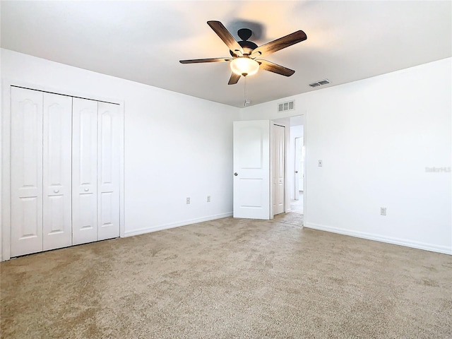 unfurnished bedroom featuring light carpet, a closet, and ceiling fan