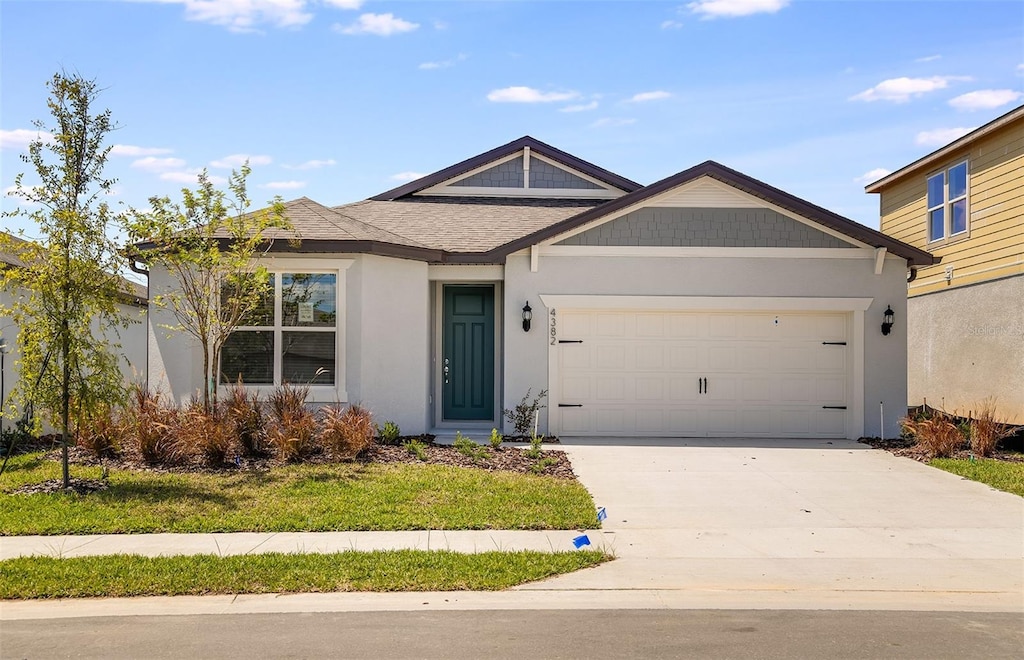 view of front of house featuring a garage, driveway, a shingled roof, and stucco siding