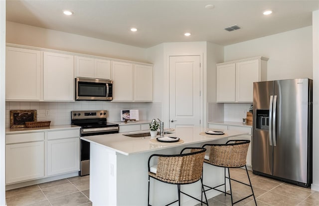 kitchen featuring appliances with stainless steel finishes, white cabinetry, and a kitchen island with sink