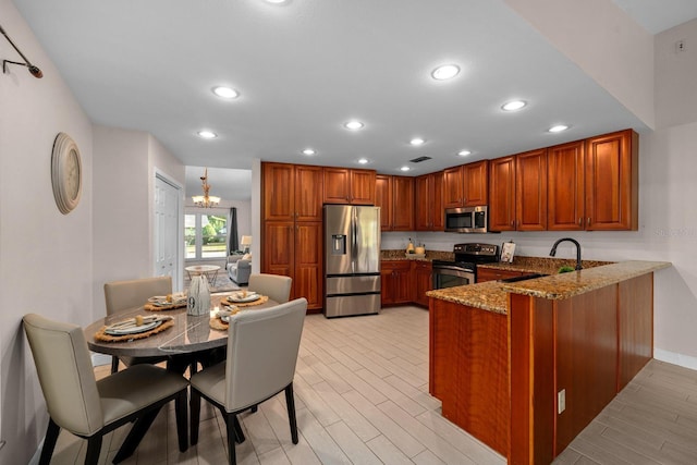 2618 Crestfield Dr, Valrico, FL 33596 - kitchen featuring stainless steel appliances, a peninsula, dark stone countertops, brown cabinets, and recessed lighting