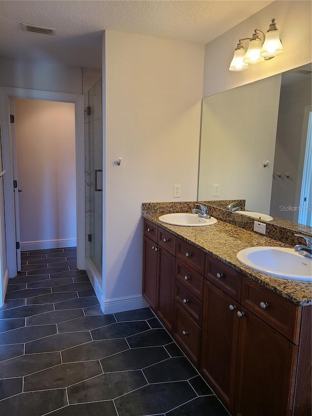 bathroom with a textured ceiling, tile patterned flooring, and double sink vanity