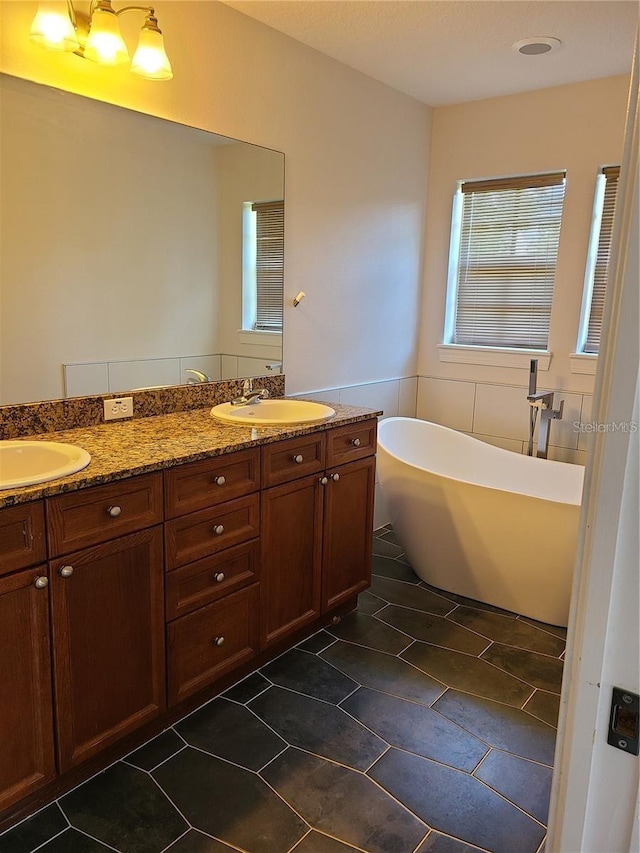 bathroom with dual vanity, tile patterned floors, a healthy amount of sunlight, and a bathing tub