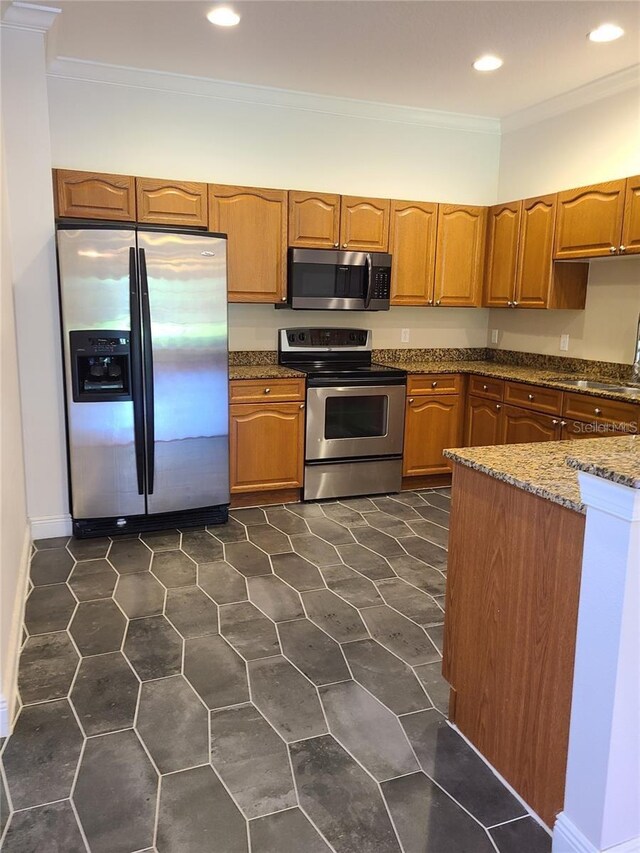 kitchen with stone counters, appliances with stainless steel finishes, ornamental molding, and sink