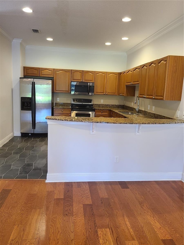 kitchen featuring sink, dark stone counters, kitchen peninsula, stainless steel appliances, and crown molding