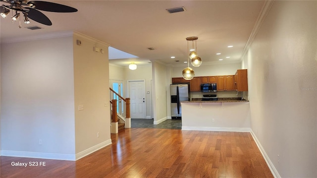 kitchen with dark hardwood / wood-style floors, a kitchen breakfast bar, ornamental molding, kitchen peninsula, and stainless steel appliances