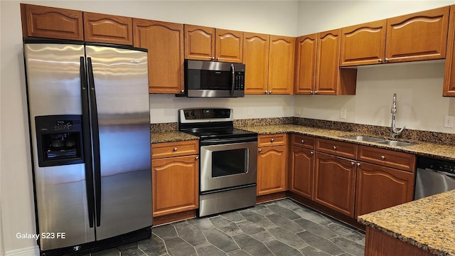 kitchen featuring stone countertops, appliances with stainless steel finishes, and sink