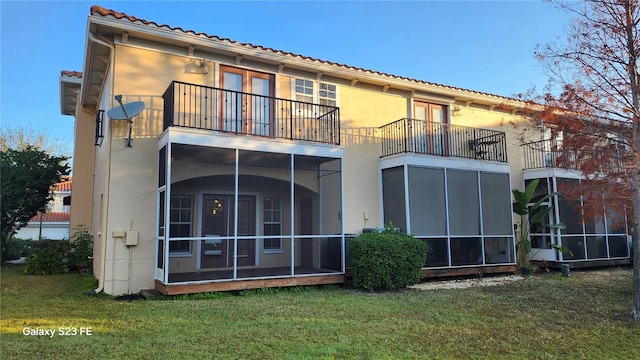 back of house featuring a yard, a sunroom, and a balcony