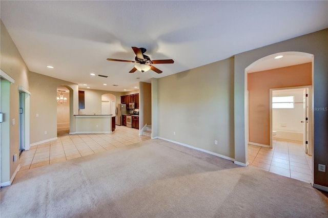 unfurnished living room with ceiling fan with notable chandelier and light carpet