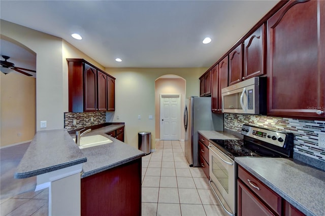 kitchen with sink, ceiling fan, appliances with stainless steel finishes, tasteful backsplash, and kitchen peninsula