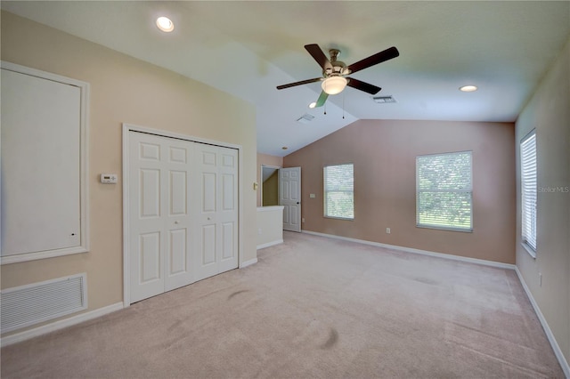 unfurnished bedroom featuring ceiling fan, lofted ceiling, and light colored carpet